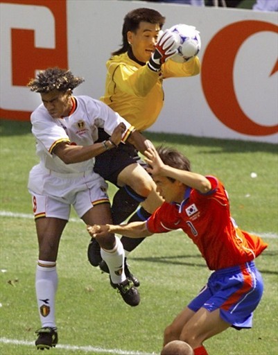 جام جهانی 1998|مهاجم بلژیکی، لوئیس اولیویرا (چپ) به هوا می پرد، زمانی که دروازه بان کره جنوبی، کیم بیونگ، مهار توپ را در دست می گیرد. گروه E جام جهانی 1998 فرانسه، 25 ژوئن، وزشگاه پارک دپرینس، پاریس.