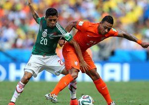 ممفیس دیپای - خاویِر آکینو|تقابل ممفیس دیپای از هلند با بازیکن مکزیک ، خاویِر آکینو برای گرفتن توپ.