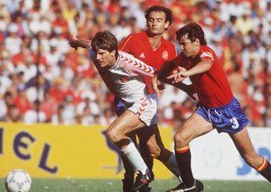 جام جهانی 1986|مایکل لادروپ از تیم دانمارک، از میان خوزه کاماچو و ریکاردو گالجو از تیم اسپانیا می گذرد. مرحله ی 16 تیم نهایی جام جهانی 1986 مکزیک. دانمارکی ها از روی پنالتی یک گل پیش می افتند اما اسپانیا با گلزنی امیلیو بوتراگوئنو در نهایت بازی را 5-1 به سود خود تمام می کنند.