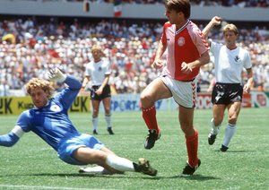 جام جهانی 1986|مایکل لادروپ از دانمارک، تحت فشار دروازه بان آلمان غربی، تونی شوماخر، در جریان دیدار تیمش برابر آلمان غربی در گروه E جام جهانی 1986 مکزیک، به سمت دروازه شلیک می کند.