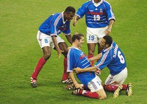 جام جهانی 1998|هم تیمی های زیدان، یوری ژورکائف، کریستین کارمبو و مارسل دسایی، پس از آن که زیدان گل نخست تیمش برابر برزیل در فینال جام جهانی 1998 را به ثمر می رساند به او تبریک می گویند. آبی ها در این دیدار 3-0 به پیروزی رسیدند. زیدان در این دیدار دو بار گلزنی کرد.