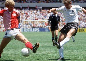 جام جهانی 1986|جام جهانی 1986، کوئرتارو، مکزیک، 13 ژوئن 1986، دانمارک 2 – آلمان غربی 0. مورتن اولسن از تیم دانمارک تلاش می کند تا شوت رودی فولر از تیم آلمان غربی را بلوکه کند.